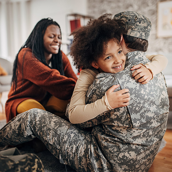 military dad in uniform hugging his child