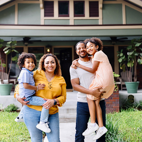 family of four standing outside new home
